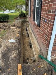 After all the piers were installed to the proper depth, we transferred the home's weight onto them by fastening our L-shaped brackets securely to both the pier and the underside of the footing.