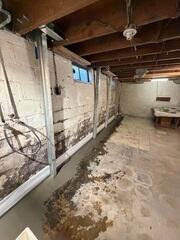 We also braced more of the same wall, just in a different room of the basement. We fitted our drainage system underneath the floor in this area as well, and we ran it underneath the interior wall, (seen on the far side of this photo) to the same sump pump, (as seen in the previous photo). However, this section of the wall was not as severely bowed, so we didn't need to straighten it out immediately. Instead, for this section, we can straighten the wall out gradually over time through annual service visits.