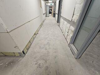 Interior hallway during renovation, showing the existing uneven concrete floor slab requiring precision leveling before final finishes can be applied.