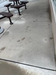 This pre-lift image clearly shows the severe settlement of concrete slabs outside the busy restaurant caused by ground erosion. The resulting uneven panels created dangerous, visible trip hazards and immediately exposed the property owner to liability concerns.