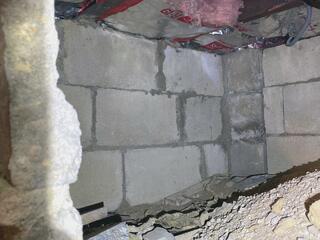 The porous cinder block walls let outside air and moisture seep into the small crawl space, creating drafts and increasing the risk of mold and water damage.