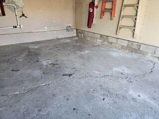 A significant diagonal crack spans the floor, caused by the concrete buckling over empty voids in the soil. Visible surface pitting also shows the impact of Alliston's harsh winter salt and freeze-thaw cycles.