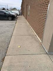 The commercial walkway exhibited significant settlement, resulting in uneven slabs and a prominent gap along the exterior wall. This separation created immediate trip hazards and allowed water to bypass the surface, leading to further sub-base erosion.