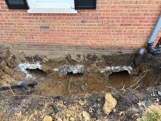 This photo shows the three cavities we dug underneath the garage before we started drilling our piers. On the left side of this hole, you can see one of our piers not yet drilled in. These piers have DNA-shaped helixes wrapped around them, which allows us to screw them deep into the earth.