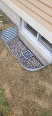 window well installation and filled with crushed stone and a drain cap to help filter out debris