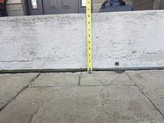 A detailed shot using a measuring tape to show the exact depth of the settlement. Identifying the precise amount of lift needed ensures the walkway is returned to its original, level position.