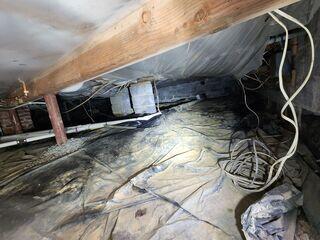 Before encapsulation, the crawl space was cluttered with debris and showed clear signs of dampness and poor insulation.