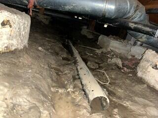 Standing water in the crawl space, causing erosion of the soil.