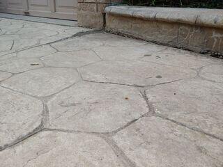 After our poly-injection process, the walkway was lifted and aligned with the brickwork. The gaps were eliminated, and the small injection points are nearly invisible, preserving the stamped concrete's aesthetic.