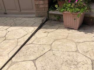 A close-up shows a deep void where the walkway had pulled away from the garage and brick foundation. This gap wasn't just an eyesore; it allowed water to pool, further compromising the soil underneath.