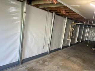 This was what the shearing wall looked like after we repaired it. The braces will stop this wall from moving and the waterproofing system at the bottom will keep the basement dry. No jackhammering needed for this wall repair system. Another note, normally we would create holes at the bases of the beams to allow water to filter through whatever type of drainage system we used. However, this was not needed as there is already room behind the braces along the bottom most row of block for water to channel through. We were able to use the shearing to our advantage in this regard.