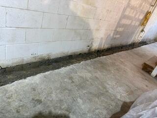 This photo shows the jackhammering we did along the rest of the walls to make room for our normal WaterGuard subfloor drains. These walls weren't shearing, so we were safe to do so. You can also see the weep holes we drilled in the trenches through the blocks.