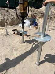 Installing helical pier 10"-12"-14" lead section with 14" extension in foreground