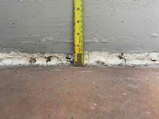 A close-up look at the home's foundation reveals the true scale of the problem: a 1.5-inch drop. This measurement illustrates the substantial void that had formed beneath the concrete, resulting in a dangerous trip hazard and a slope that directed water toward the basement instead of away from it.
