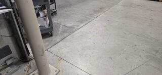 Uneven joints and wear patterns across the warehouse floor, signaling that the slabs have lost subgrade support and are beginning to shift.