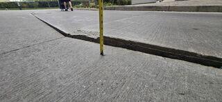 The tape measure reveals the true extent of the danger: a nearly 4-inch ledge. This isn't just a bump-it's a massive trip hazard and a liability for the property. This photo highlights the deep void underneath that we filled with our high-density polymer to bring the slab back toward a safe, level position.
