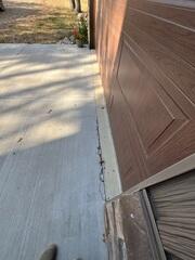 A close-up of where the garage and driveway meet where chipping and cracks can be seen