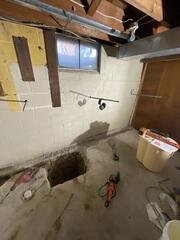 Mid-Install 1: Trench is dug around perimeter of basement for WaterGuard. Threaded rods extended through the wall to connect anchors.