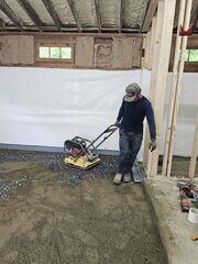 The crew used a mechanical plate compactor to firmly compact the base material before pouring concrete. This created a stable, even foundation for the new garage floor.