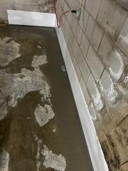 The crew installs WaterGuard around the basement perimeter to drain wall leaks.