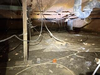 An unfinished crawl space with an aging ground barrier, exposed structural supports, and areas vulnerable to ground moisture. The space needed improved drainage, structural support, and a properly sealed moisture barrier to provide better long-term protection for the home.