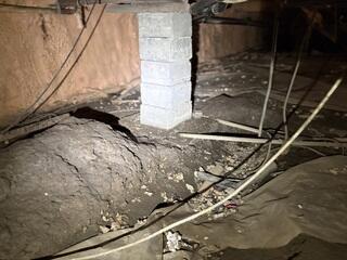 An unfinished crawl space with an aging ground barrier, exposed structural supports, and areas vulnerable to ground moisture. The space needed improved drainage, structural support, and a properly sealed moisture barrier to provide better long-term protection for the home.