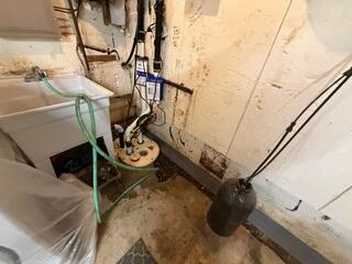 The crew installs a new TripleSafe sump pump to pump out water from the drainage system.
