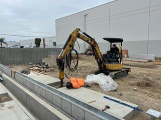 Helical piles being installed to final elevation with mini excavator