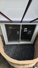 RockWell Egress Window Well - A durable, one-piece window well featuring built-in steps, rigid construction, and a realistic stone-textured appearance.