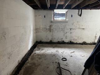 Before work began in this basement, multiple horizontal and vertical cracks were visible throughout the unfinished foundation and block walls. During heavy rain, water was also entering through the bottom of the walls, contributing to recurring basement flooding.