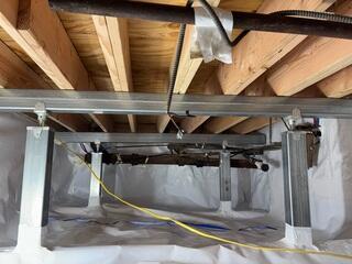 The old joists were removed and replaced with new joists running front to back, while two rows of SmartJacks and a supplemental support beam were installed to create new support points for the floor system.