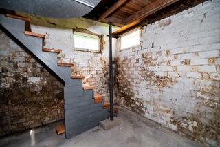 The older brick foundation walls in this basement showed significant signs of deterioration, including gaps in the masonry, loose sections, heavy brown discoloration, and visible water damage.