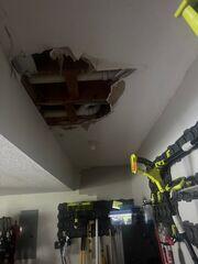 Damaged garage ceiling with drywall removed and the ceiling cavity exposed before the repair process began.