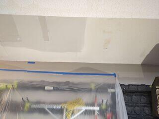 New drywall installed and finished over the garage ceiling opening in preparation for matching the existing popcorn texture.