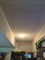 Completed garage ceiling repair in Olathe, KS with new popcorn texture blended across the repaired section.