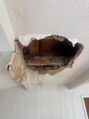 Close-up of the damaged ceiling opening and exposed framing.