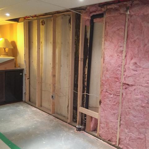 A view of the previously finished area of the basement where seepage from the wall and footing caused damage to the insulation and drywall.