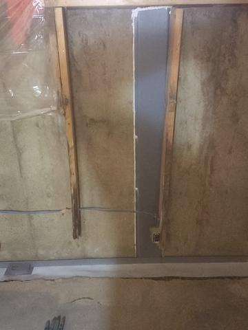 A view of the window well on the interior of the home during the WellDuct® installation. The gray plastic fitting placed on the inside basement wall, directing water down into the WaterGuard® below-floor drain system.
