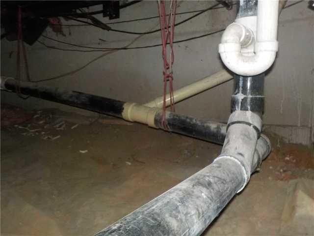 This kind of debris settling on pipes can be a sign of ambient moisture; as the water evaporates it leaves behind any dirt it carried with it. It can also just be a side effect of a dirt floor. Regardless, it's ugly and gross to navigate.