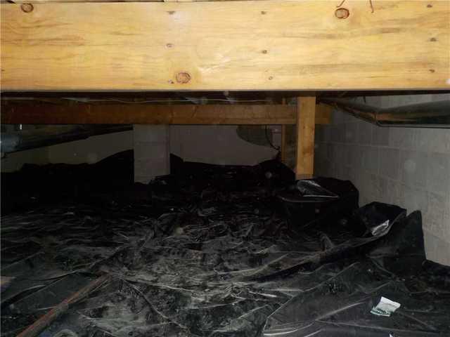 While they thought there was a vapor barrier in place in the crawl space, it was actually this plastic sheeting. Since it isn't affixed to anything or creating any sort of seal, it's more like a heavy tarp that leaves the crawl space susceptible to moisture issues.