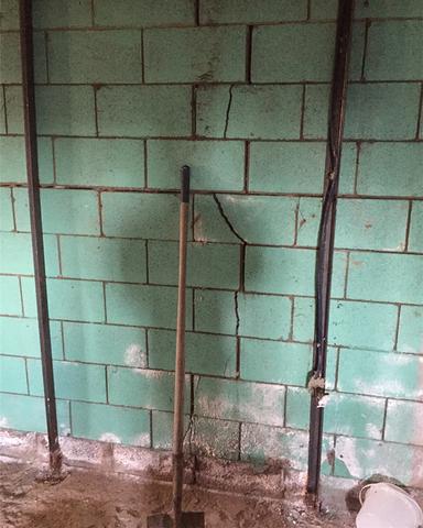 Inside the basement of the home where a portion of the cinder-block foundation wall has cracked and is also bowing inwards.