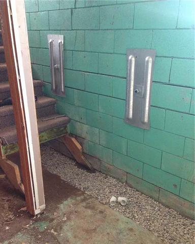 Another view inside the basement of the home the where the Geo-Lock™ wall anchor system has been installed along portions of the bowing cinder-block foundation wall next the to stairs.