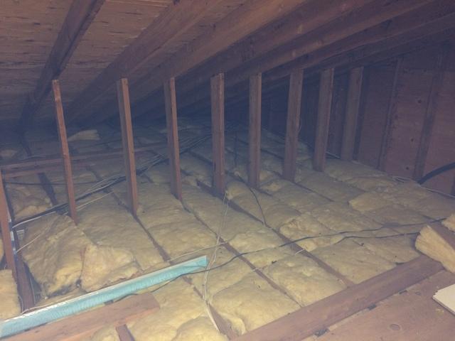 Obsolete and dirty fiberglass insulation covers the attic.