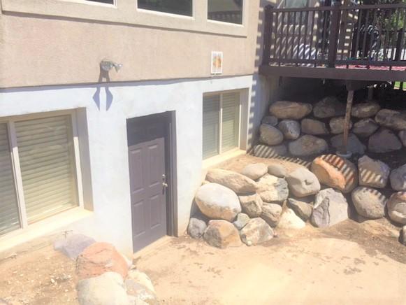 We installed a Trench Drain near the door, and sump pump with a drainage line to divert the water around the wall and away from the door.