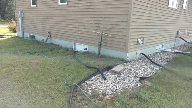 This yard is filled with pipes and hoses connected to the house to keep water away, however, it's extremely messy and very inconvenient.