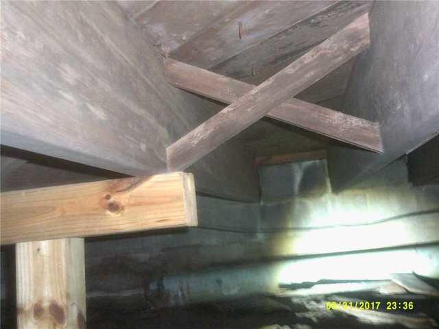 Mold is visible on the joists throughout the crawl space. The presence of new supplementary support beams on the left show that the original beams are slowly degrading from exposure to mold and moisture.