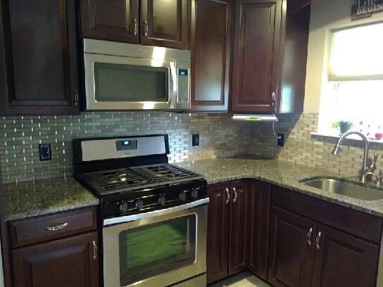 View of the finished kitchen. We installed the granite counter top, mahogany cabinets and shelves, stainless steel appliances, windows and kitchen sink. Installed tile wall for sleek finished look.