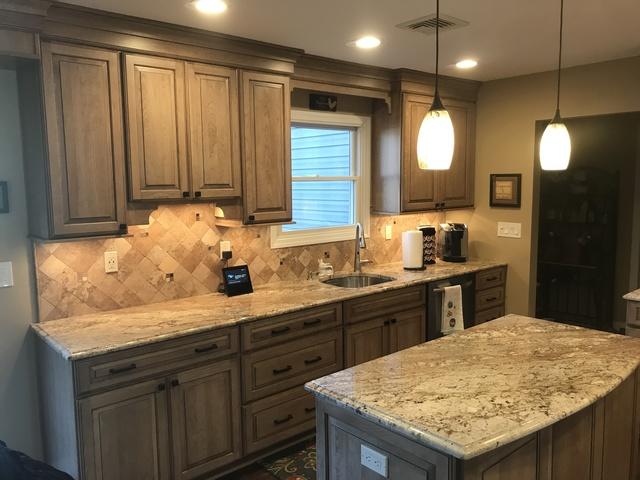 Another angle of the kitchen, including the sink and counter top and overhead shelves.