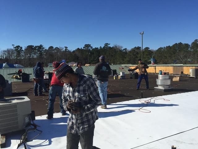 Our team in the middle of laying down the new TPO roofing.