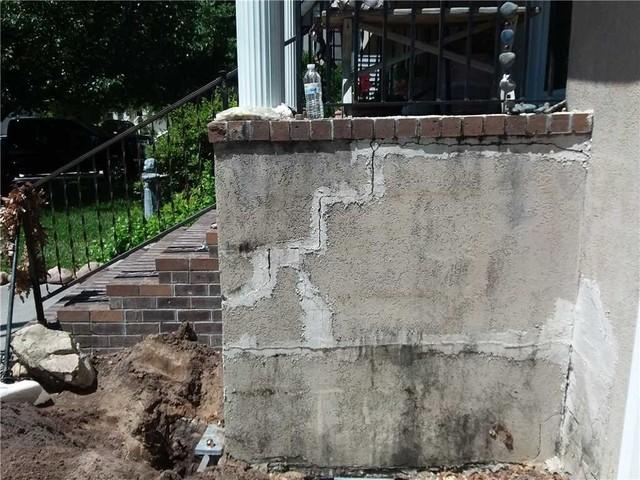 Notice the staircase patterned crack going up along the side of the porch, a common telltale sign of foundation issues.